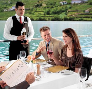 Picture of steward offering wine to diners eating outside on a river boat cruise