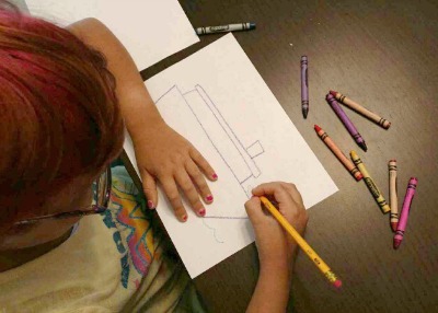 picture of a child drawing a cruise ship for her journal.